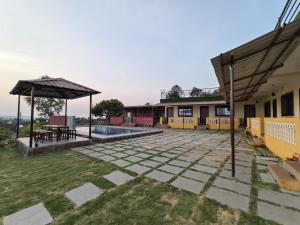 un patio con patio y una casa en Shayadri Farmhouse, en Mahabaleshwar