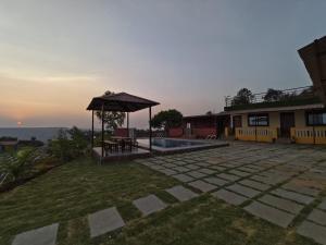 un patio trasero con cenador y una casa en Shayadri Farmhouse, en Mahabaleshwar