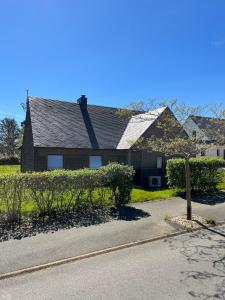 a house with a tree in front of a street at Belle maison en bois Perros - La lande in Perros-Guirec