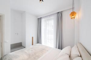 a white bedroom with a large bed and a window at SunilioS Apartments Lefkada in Lefkada Town