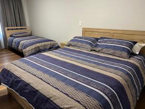 a bedroom with two beds with blue and white striped sheets at The Morrison Motel in Swan View