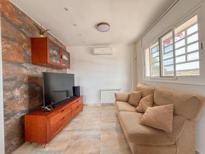 uma sala de estar com um sofá e uma televisão de ecrã plano em Clauhomes Golf and Sea em Tarragona