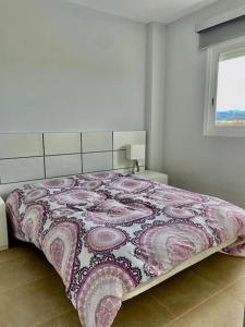 1 dormitorio con 1 cama con manta rosa y blanca en Apartamento frente al mar, en Oliva