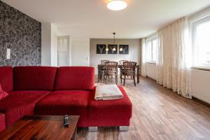 een woonkamer met een rode bank en een tafel bij Ferienwohnung "Tee Tied" 35225 in Hesel