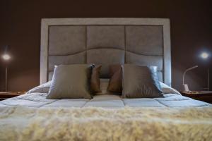 a large bed with a white bedspread and pillows at Le Cento Sculture Apartment in Belpasso