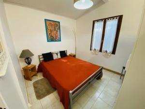 a bedroom with a red bed and a window at Gîtes de la villa du pin in Ruoms