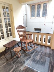 a rocking chair and a table in a room with windows at Brindaven in Mysore