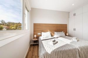 a white bedroom with a large bed and a window at White Tree Rooms and Apartments in O Pedrouzo
