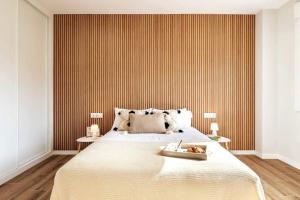 a bedroom with a large bed with a striped wall at Apartamento White Tree by Arca Azahar in O Pedrouzo