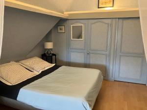 a bedroom with a white bed and a door at La Noisetiere in Noyers-sur-Cher