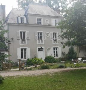 a large white house with white shutters on it at Le petit plessis in Ruaudin