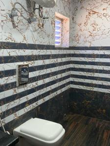 a bathroom with blue and white striped walls and a toilet at Dayal International - New Digha in Digha