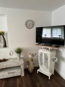 a living room with a tv and a radiator and a clock at Ferienwohnung am Jacobsweg in Hohenpeißenberg