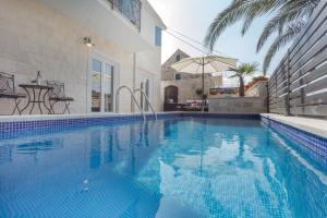 a swimming pool with an umbrella next to a house at Villa Capitis in the Centre - Private Pool Villa & Balcony Apartment with Spectacular View-No Pool in Hvar