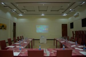 una sala de reuniones con mesas y sillas y una pantalla en La Vista Garden Hotel, en Turiani 17 fotos más