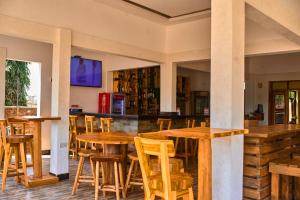 un bar con mesas de madera y sillas en un restaurante en La Vista Garden Hotel, en Turiani