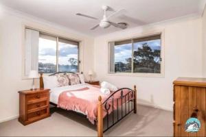 a bedroom with a bed and two windows at Aircabin - Tuggerawong - Lake Front - 9 Beds House in Karraganbah