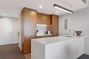 a kitchen with a white counter and wooden cabinets at Parque on St Kilda - 02532 in Melbourne