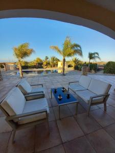 een patio met banken, een tafel en palmbomen bij Hideaway Villa in Phrenaros