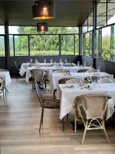 un ristorante con tavoli e sedie bianchi e finestre di Porsenna Resort a Villastrada