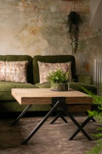 Akasha Spa Retreat Cottage في Welton: غرفة معيشة مع أريكة خضراء وطاولة قهوة