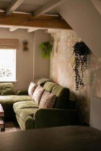Akasha Spa Retreat Cottage في Welton: غرفة معيشة مع كنب اخضر في غرفة