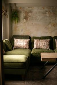 Akasha Spa Retreat Cottage في Welton: غرفة معيشة مع أريكة خضراء وطاولة