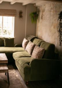 a living room with a green couch and a window at Akasha Spa Retreat Cottage in Welton