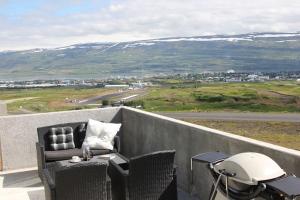 uma varanda com uma mesa e cadeiras e um capacete em Private cottage, elegance & amazing view em Akureyri