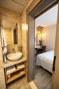 baño con lavabo, cama y espejo en Aktas Hotel en Mersin