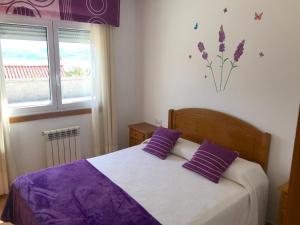 a bedroom with a bed with purple pillows and a window at APARTAMENTOS CANADA 2 in Raxó +66 photos
