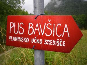 a red sign on a pole in a field at PUS Bavšica in Log pod Mangartom