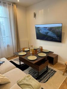 ein Wohnzimmer mit einem Tisch und einem TV an der Wand in der Unterkunft Cocon boisé près de Paris in Aulnay-sous-Bois