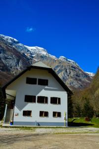 a white building with a mountain in the background at PUS Bavšica in Log pod Mangartom