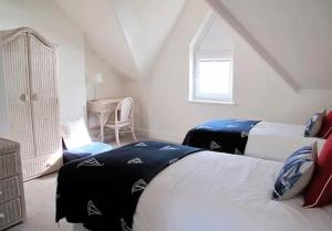 Un dormitorio abuhardillado con dos camas y una ventana. en Ivy House - Seafront house with garden seating and stunning sea views! - Ocholo Villas, en Filey