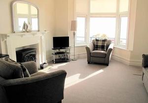 Una sala de estar con dos sillas y una chimenea. en Ivy House - Seafront house with garden seating and stunning sea views! - Ocholo Villas, en Filey