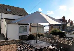 Una mesa y sillas con una sombrilla en un patio. en Ivy House - Seafront house with garden seating and stunning sea views! - Ocholo Villas, en Filey