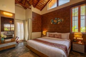 a bedroom with a large bed and a brick wall at amã Stays & Trails Vivid Foliage Kasargod , Mangalore in Ullāl +55 photos