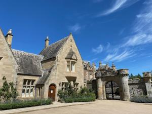 an old stone house with a gate and a blue sky at Mill Cottage Garden Studio nr Melrose in Melrose