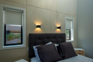 a bedroom with a bed with two windows at Jacks Lodge Townhouse in Hanmer Springs