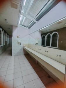 a bathroom with a long row of sinks and mirrors at Mang Ben Dormitory Kaliraya in Manila