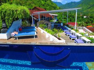 una piscina en un complejo con tumbonas azules en Waenis Sunset View Hotel and Restaurant, Amed, Bali, en Amed