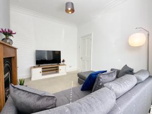 a living room with a couch and a tv at Wrightson House by Blue Skies Stays in Stockton-on-Tees