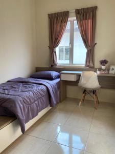 een slaapkamer met een bed, een bureau en een raam bij Homestay Khan'Da Teluk Intan in Teluk Intan