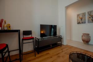 uma sala de estar com uma televisão de ecrã plano e cadeiras em Elegant Apartment 28 San Giacomo em Trieste
