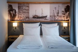 ein Bett mit zwei Kissen und einem Bild eines Schiffes in der Unterkunft 4Hafenzeiten - Ferienwohnung NIE 6 Venus in Timmendorfer Strand