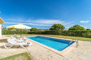a swimming pool with a chair and an umbrella at Villa Mina - Large house sleeps 9, walk to beach, golf and shops in Guia