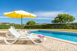 a pair of chairs and an umbrella next to a swimming pool at Villa Mina - Large house sleeps 9, walk to beach, golf and shops in Guia