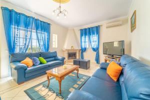 a living room with blue couches and a tv at Villa Mina - Large house sleeps 9, walk to beach, golf and shops in Guia