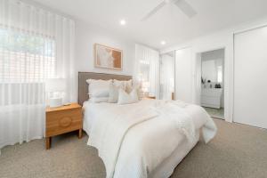 a white bedroom with a large bed and a window at The Grape Escape Location and style on Shiraz Trail in McLaren Vale